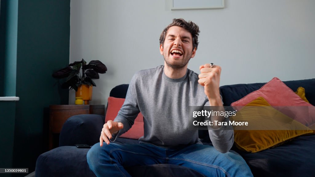 Man celebrating on sofa in house