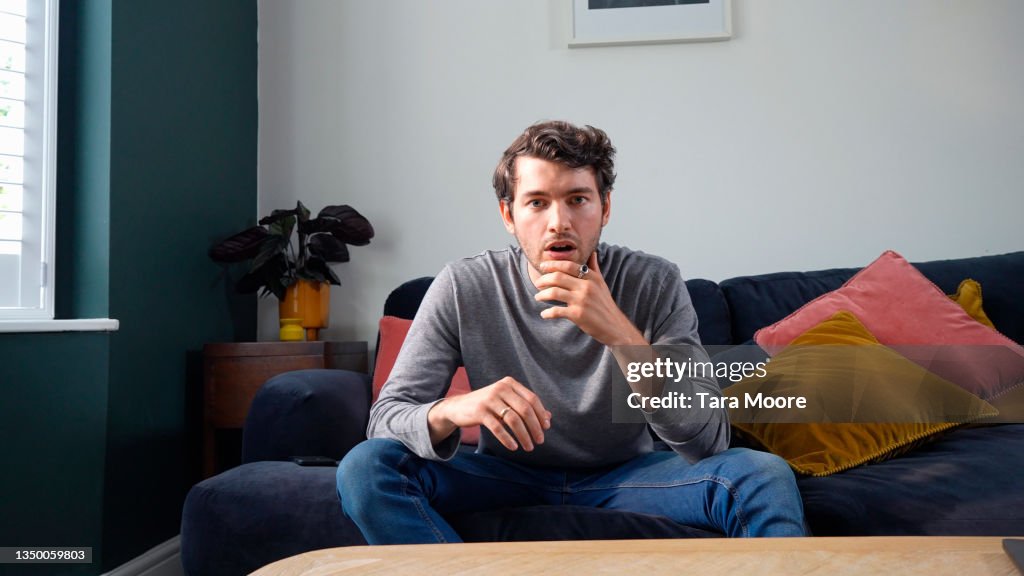 Young man looking shocked on sofa