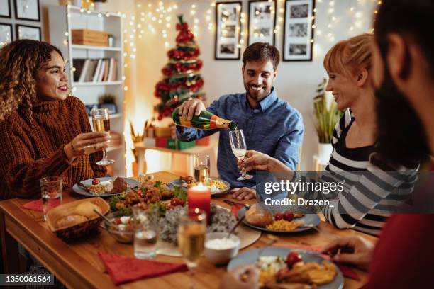 friends celebrate christmas at home and eating dinner - adult laughing christmas stock pictures, royalty-free photos & images