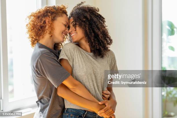 happy girlfriends in a tender moment at home - lesbische stockfoto's en -beelden