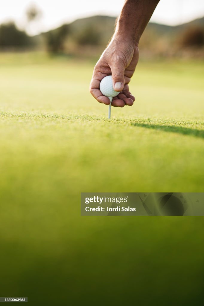 Golfer's gloved hand teeing up