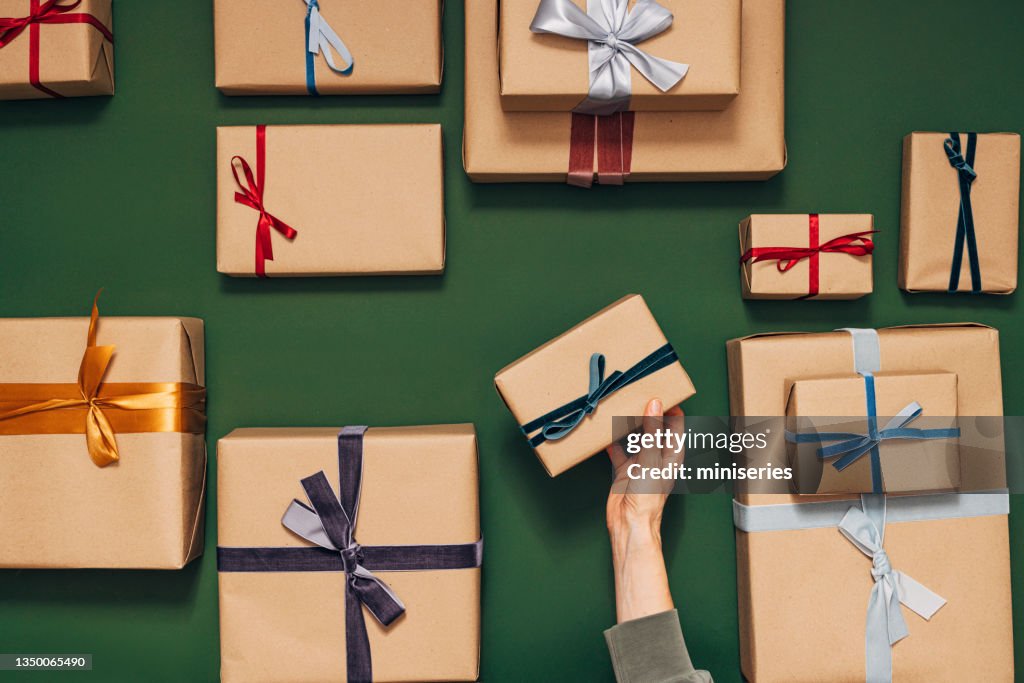 Anonymous Person Holding One of Many Gift Boxes on a Green Background