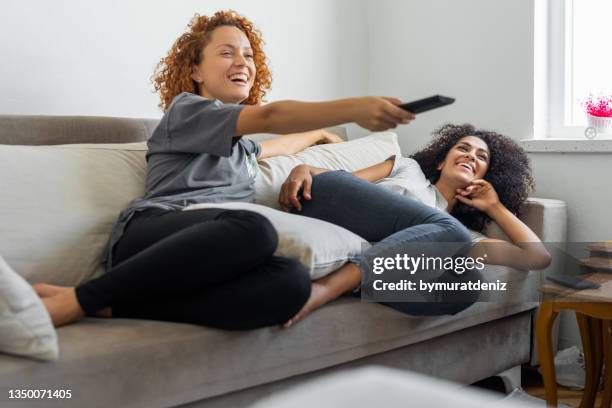girlfriends are watching their favorite tv show while sitting on the couch - couple tv bildbanksfoton och bilder