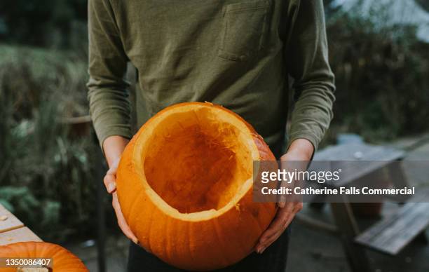 an older child holds an empty carved out orange pumpkin, ready to be carved for a traditional hallowe'en festival, - carving craft activity stock pictures, royalty-free photos & images