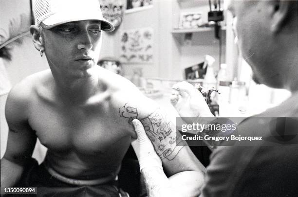 Rapper Eminem getting tattooed by artist Mister Cartoon at Bob & Charlie Roberts Spotlight Tattoo shop on May 8th, 1999 in Los Angeles, California.