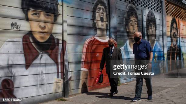 Citizens walk by a mural depicting Diego Armando Maradona on differrent stages of his life at Diego Armando Maradona Stadium on October 21, 2021 in...