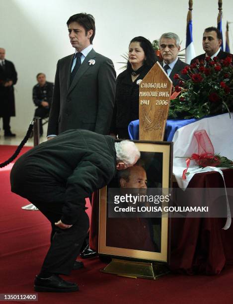 An elderly supporter of late former Yugoslav President Slobodan Milosevic mourns in front of his coffin drapped with a Serbian flag at the Museum of...