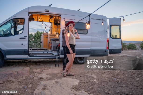 hippie girlfriend dancing with boyfriend near van in nature under edison bulbs in the desert - camper van imagens e fotografias de stock