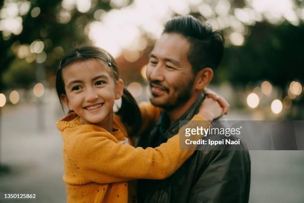 young girl and her father hugging at dusk - persona de color fotografías e imágenes de stock