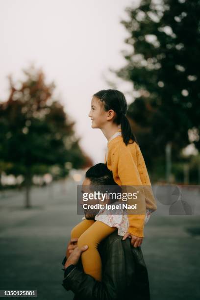 father carrying young daughter on shoulders at dusk - 肩車 ストックフォトと画像