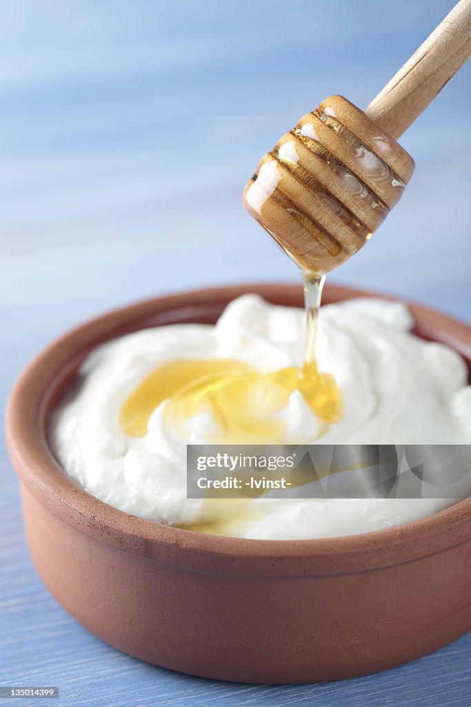 Bowl of Greek yogurt being topped with honey
