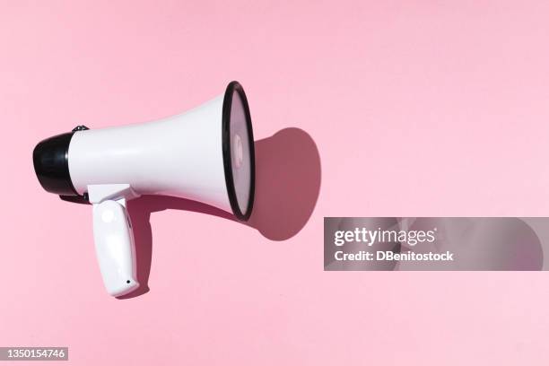 white megaphone with black trim on the left and copy space on the right, on a pink background. shout, message, announcement and news concept. - horn press stock pictures, royalty-free photos & images