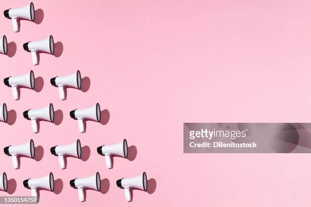 white megaphones pattern with black ornament on pink background on the left side, with copy space. shout, message, announcement and news concept. - megaphone stock pictures, royalty-free photos & images