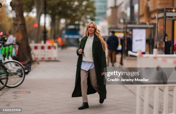 Blanca Miro wearing a Mango green coat, a white pullover and blue shirt, a beige pants and black boots on October 27, 2021 in Berlin, Germany.