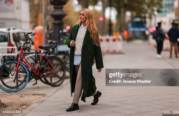 Blanca Miro wearing a Mango green coat, a white pullover and blue shirt, a beige pants and black boots on October 27, 2021 in Berlin, Germany.