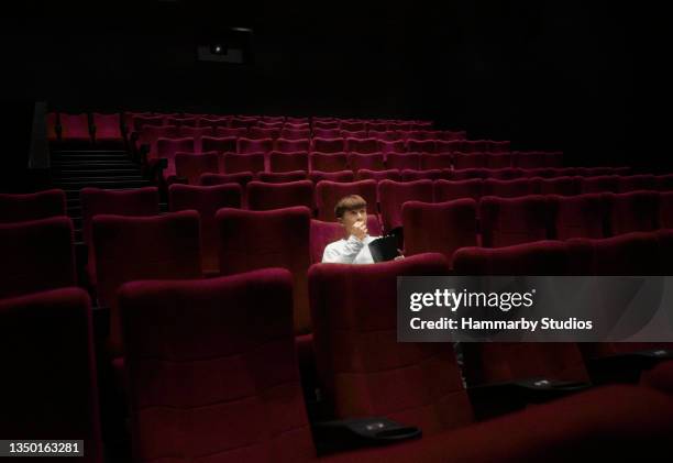 portrait of a teenage boy watching a movie in a movie theater - one film stock pictures, royalty-free photos & images