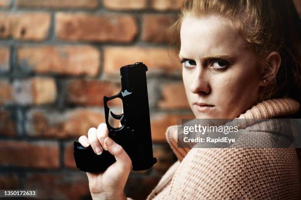 young redhead woman holding a gun and looking - pistool handwapen stockfoto's en -beelden