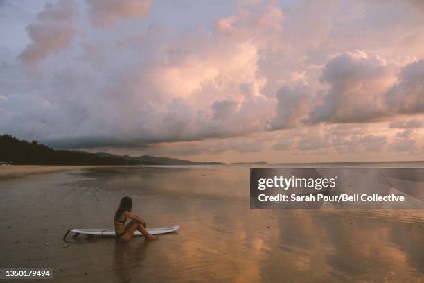 Young adult female on surf vacation in Thailand at sunset