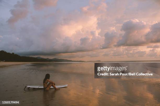 Young adult female on surf vacation in Thailand at sunset