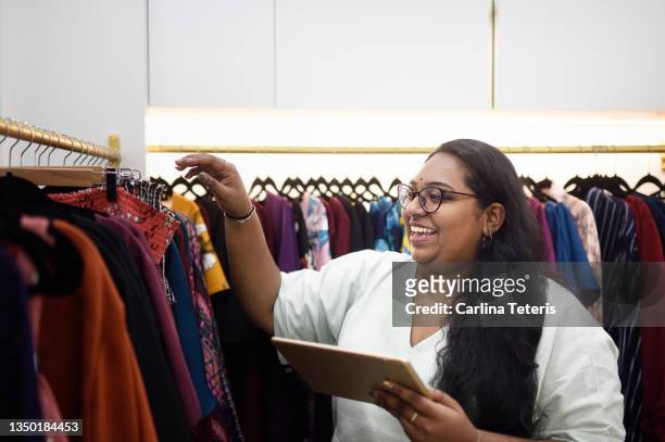 woman checking inventory in a clothing shop with a tablet - chubby man shopping stock-fotos und bilder