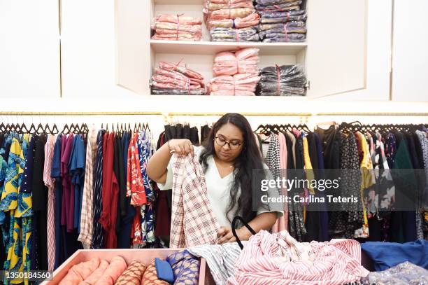 shop assistant organizing merchandise in a clothing shop - chubby man shopping stock-fotos und bilder