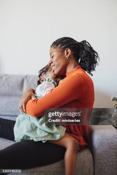 happy mother embracing her daughter at home - braided hairstyles for african american girls stock pictures, royalty-free photos & images