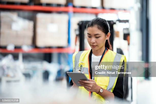 days of inventory on hand in distribution warehouse. asian female inventory control staff using a digital tablet to inventory check real-time and report inventory while making recommendations on which items to order and restock. - warehouse stock pictures, royalty-free photos & images