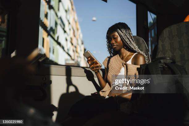 young woman using smart phone in bus during sunny day - gen z bildbanksfoton och bilder