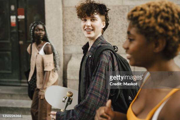 portrait of smiling teenage boy walking with young friends in city - last 16 stock-fotos und bilder