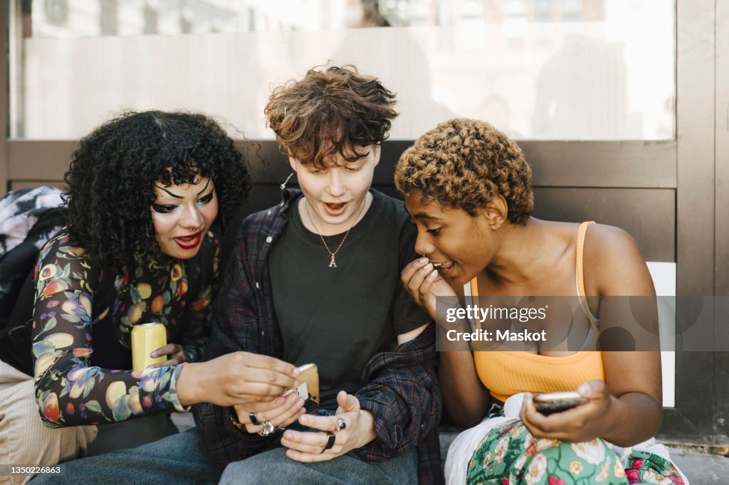 Teenage boy sharing smart phone with shocked friends