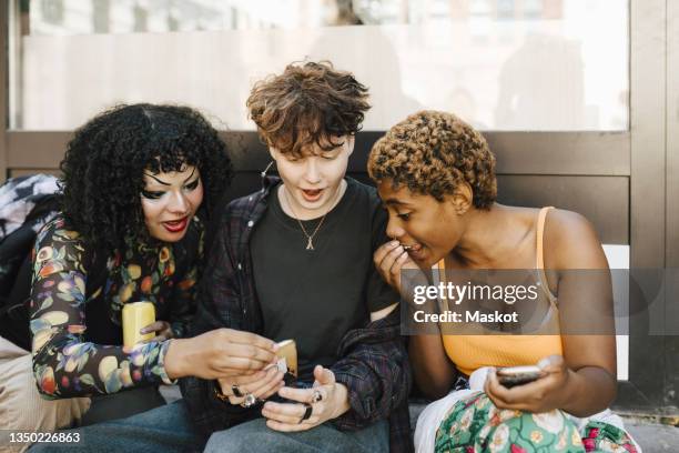 teenage boy sharing smart phone with shocked friends - teen lesbians stock pictures, royalty-free photos & images