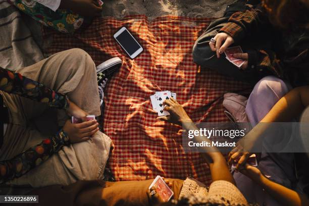 multiracial friends playing cards at beach - id cards stock-fotos und bilder