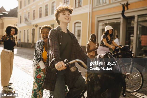 cheerful friends cycling and skateboarding on street in city - boy and girl fotografías e imágenes de stock