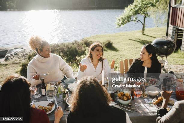 happy woman talking with female friends while enjoying dinner party at back yard on sunny day - chinese eating backyard stock pictures, royalty-free photos & images