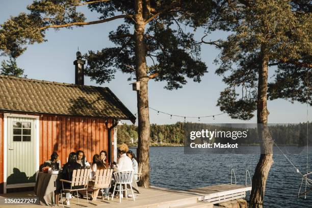 female friends having dinner at back yard on sunny day - göteborg stockfoto's en -beelden