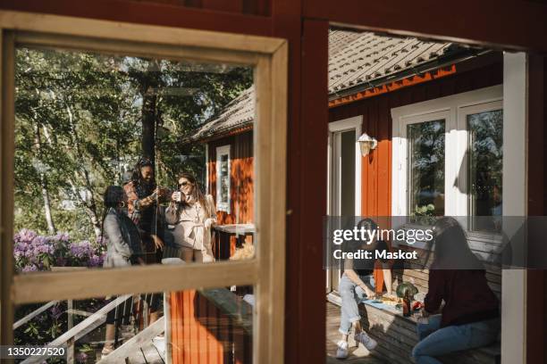 female friends enjoying dinner party at porch seen from window - porch stock pictures, royalty-free photos & images
