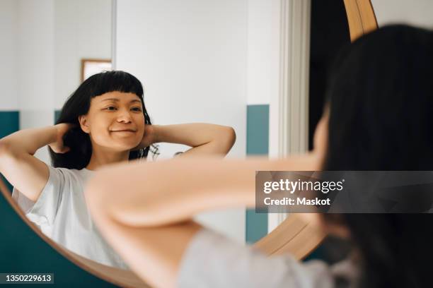 reflection of smiling woman with hand in hair at home - woman mirror stock pictures, royalty-free photos & images