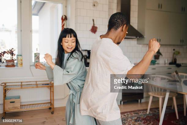 joyful female and male friend dancing at home - paar partnerschaft stock-fotos und bilder