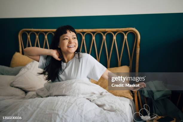 happy young woman waking up in bed at home - levantarse fotografías e imágenes de stock