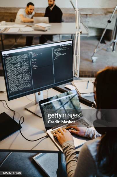 female programmer coding on laptop at table in creative office - arab on computer imagens e fotografias de stock
