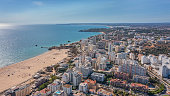 Aerial view of the city of Portimao over residential buildings, high-rise buildings, on the beach Praia de Rocha with tourists.