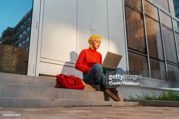 estudiante universitaria dedicada y moderna que trabaja en una computadora portátil - reds fotografías e imágenes de stock