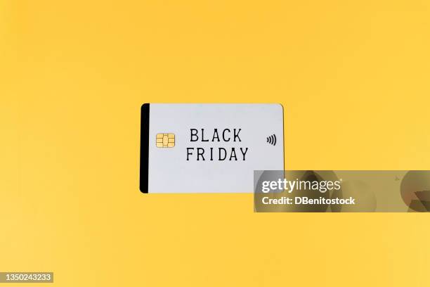 white credit card with the word 'black friday', on yellow background. black friday, shopping, commerce and credit cards concept. - fridy stock pictures, royalty-free photos & images