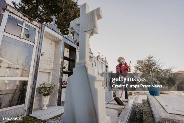 Woman cleans a tombstone at the cemetery of Santa Mariña de Dozo, on 22 October, 2021 in Cambados, Pontevedra, Galicia, Spain. This cemetery of the...