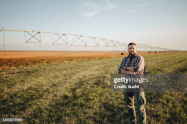jeune agriculteur debout dans un champ de blé et installant un système d�’irrigation - rancher photos et images de collection