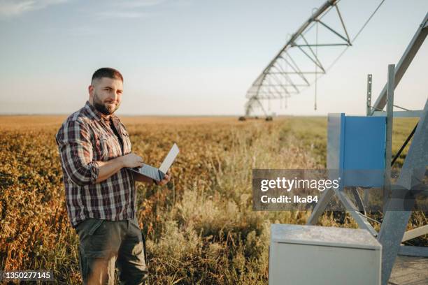 young farmer standing in wheat field and setup irrigation system - quality control inspectors stock pictures, royalty-free photos & images