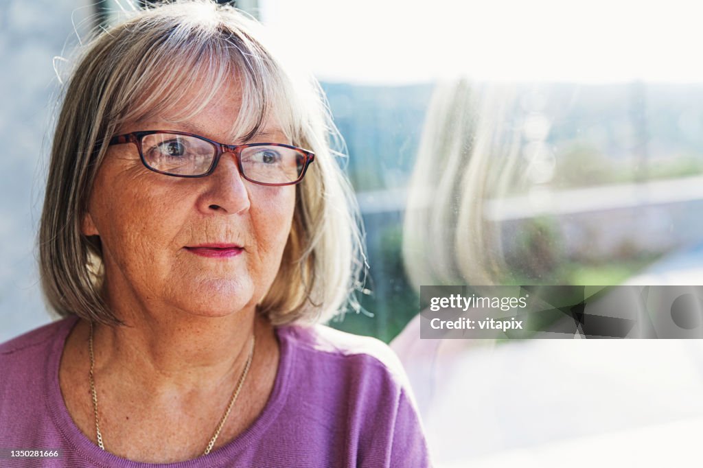 Pensive Mature Woman Looking Out of the Window