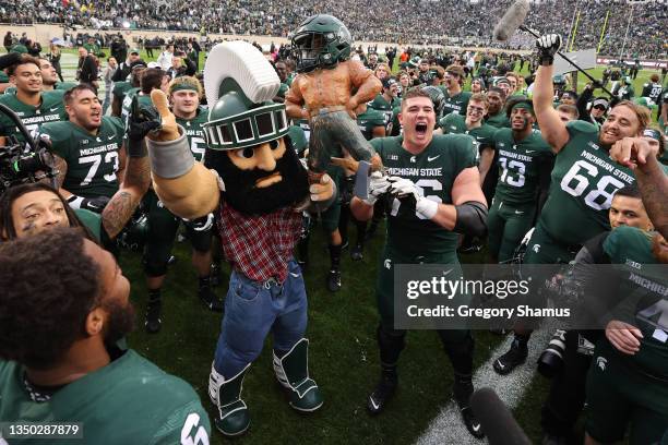 Arcuri of the Michigan State Spartans celebrates with the Paul Bunyan trophy with Sparty the Michigan State Spartans mascot after defeating Michigan...