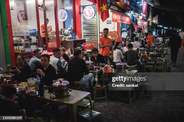 nachtaufnahme eines straßencafés voller menschen - hanoi night stock-fotos und bilder