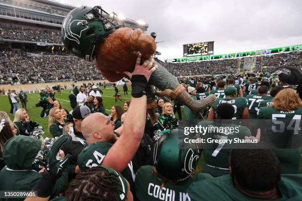 Matt Allen of the Michigan State Spartans celebrate with the Paul Bunyan trophy after a 37-33 win over the Michigan Wolverines at Spartan Stadium on...